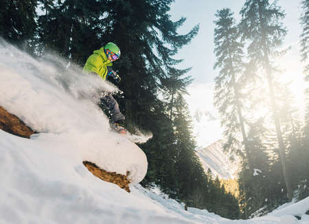 snowboarder with special equipment is riding fast, jumping, freeriding very fast in the morning mountain forestの写真素材