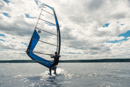 the guy in the waggon swims on the windsurf on the lake
