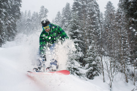 snowboarder in the forest jumping creating snow splashes