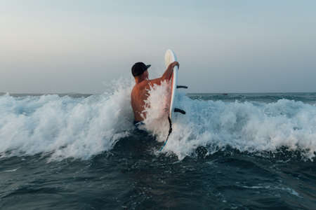 the surfer enters the ocean with a board across the wave,の写真素材