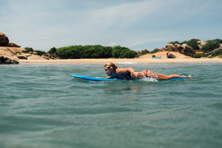 the girl floats on a surf catches a wave. Against the shore