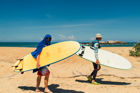 two handsome men walk on the sand beach with serf in shrilankaの写真素材