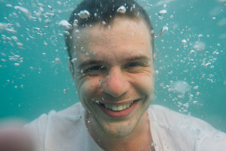 Underwater portrait of happy and smillng man in swimming pool.