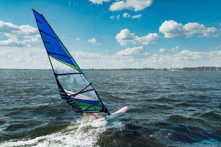 the man athlete rides the windsurf over the waves on the lakeの写真素材
