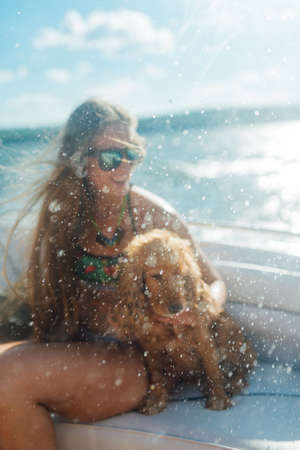 Blurry spray on the background of a girl with long hair and a dog on a boatの写真素材