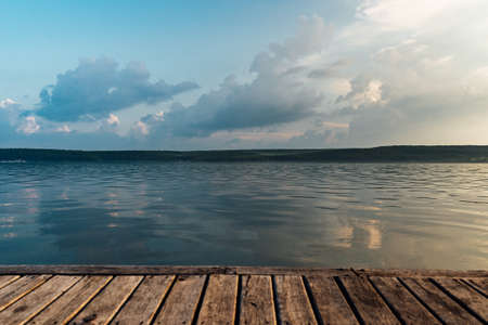 view of a large calm lake at sunset from a wooden pierの写真素材