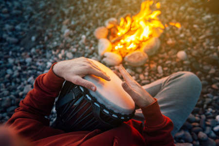percussionist playing djembe sitting by the fire, close-upの写真素材