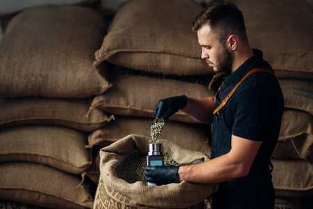 a worker pours a scoop of coffee into a device for measuring humidity from a bag, in the background...