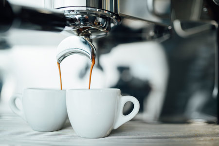 extraction of espresso from a double open-end portafilter holder into a white cupの写真素材