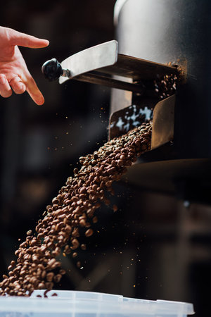 The flow of coffee beans from hand open flap of the cooling mixer of the roasting machine side viewの写真素材