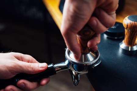 tempering coffee in portafilter on a dark background, close-upの写真素材