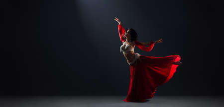 Woman in red arabic dress dancing oriental dances in arabesque poseの写真素材