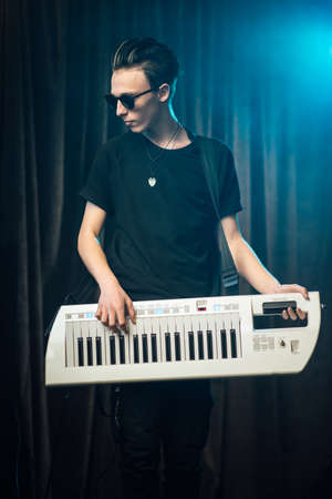 Trendy young man playing on an electronic keyboardの写真素材
