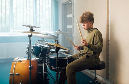 Young blond teen boy play drum kit in studio.の写真素材