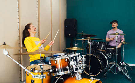 The girl behind the drum kit laughs. Music lesson with teacher.の写真素材