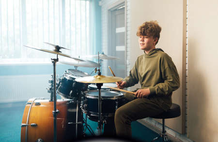 A boy enjoys music playing the drum setの写真素材