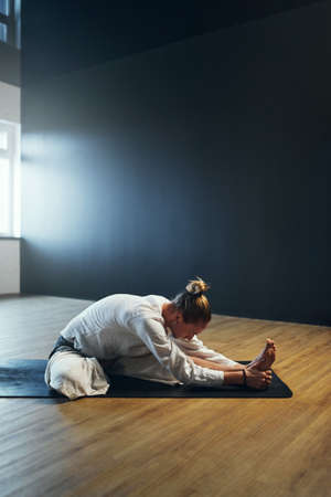 Man doing janu sirsasana. Yoga practice in the studio.の写真素材