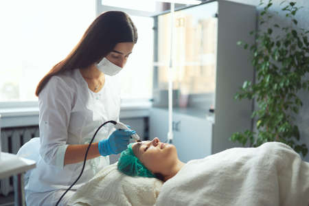 Beautician conduct ultrasonic cleaning of the face of a young girl.の写真素材