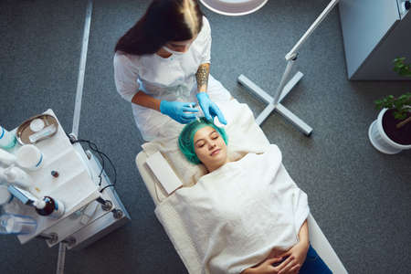 Salon worker injects cosmetic fillers into the face of a young girl.の写真素材