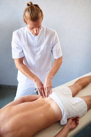 Professional back massage for patient lying on massage tableの写真素材