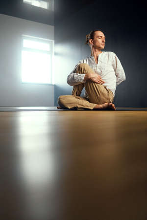 The yogi man do ardha matsyendrasana. Yoga practice in the studio.の写真素材