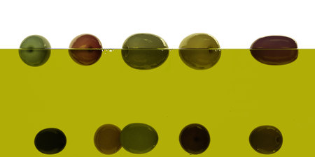 Fresh ripe various olives floating on olive oil surface semi-submerged on white background....