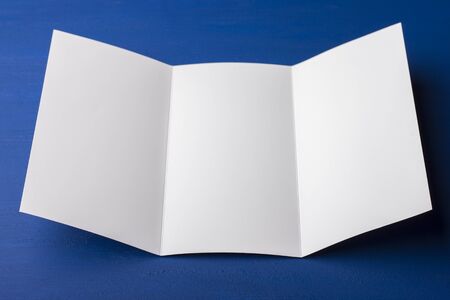 Blank tri fold brochure on blue background to replace your design or message. A mock-up for brand identification for designersの写真素材