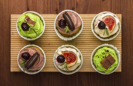 Three cupcakes on a wooden board. Wooden background. A delicious dessert. View from aboveの写真素材