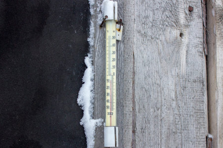Old thermometer on a wooden wall. Cold winter day 