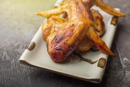 A plate of chicken wings on a dark background. Crispy grilled chicken の写真素材