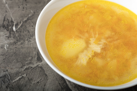 Bowl of chicken soup on a dark background. Delicious chicken brothの写真素材