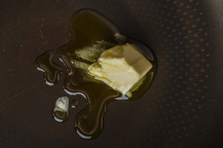 Frying pan with olive oil and a piece of butter. Cooking for breakfastの写真素材