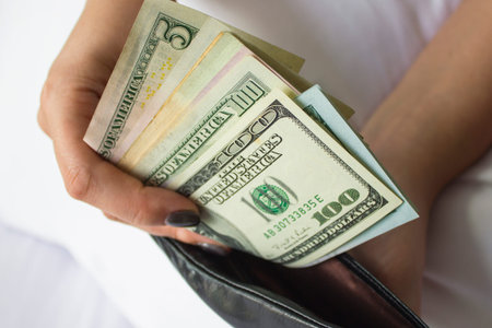 Hands hold dollar bills and a small money bag. Different banknotes 1
