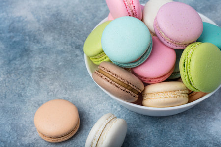 Colorful makarons in a white plate on a blue background. Copy space 2の写真素材