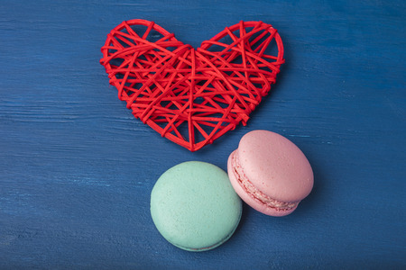 Pink and turquoise cookies, macaroni and red heart on a blue background. Close-up. Copy spaceの写真素材