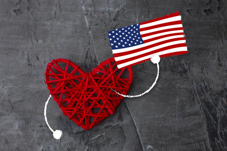 Red heart with American flag in hand. Holiday of the American flag. Dark background. Copy spaceの写真素材