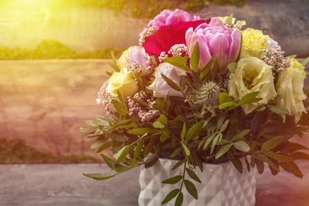 Magnificent bouquet of multi-colored roses and other flowers in a white vase, on a wooden backgroundの写真素材