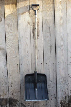 A snow shovel weighs on a wooden shed wallの写真素材
