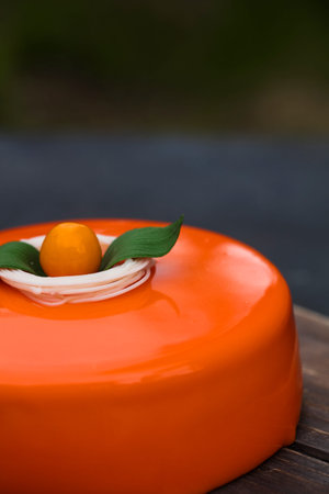 Orange cake in a mirror glaze, on a wooden trayの写真素材