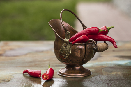 Hot peppers, fresh in a bronze pot, in a natural settingの写真素材