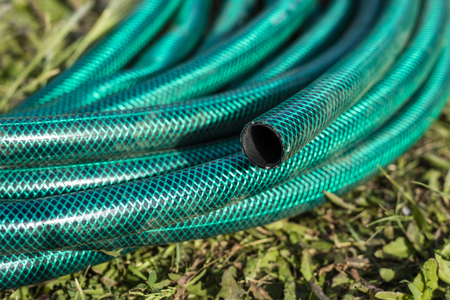Part of a garden hose wrapped up on green grass. Close-up. Copy spaceの写真素材