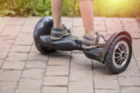 Abstract blur of a child rides on a dark electric mini saddle hinged scooterの写真素材