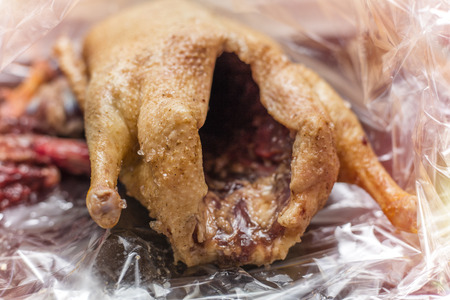 Raw duck with spices in a bag for baking on a wooden board. Close-up. Christmas themeの写真素材
