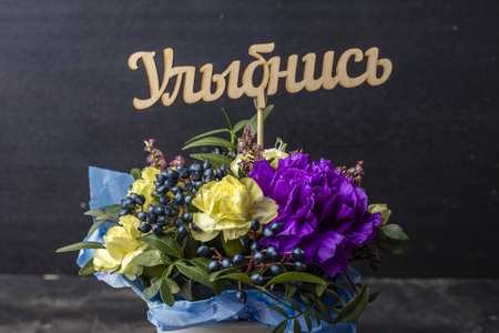 Beautiful bouquet of flowers with a sign in Russian: SMILE. Dark backgroundの写真素材