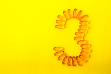 Number three of the fish oil capsules Omega 3 on a yellow background with copy space