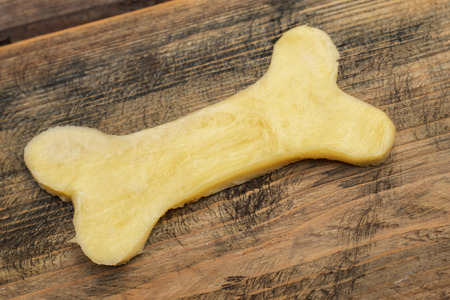 dough for cookies in the form of a bone for dogs on a wooden background. Copy spaceの写真素材
