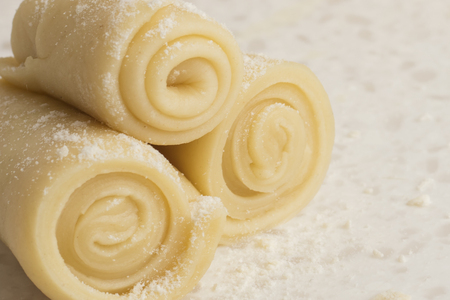 Raw twisted biscuits on white table in flour. Copy space for your textの写真素材