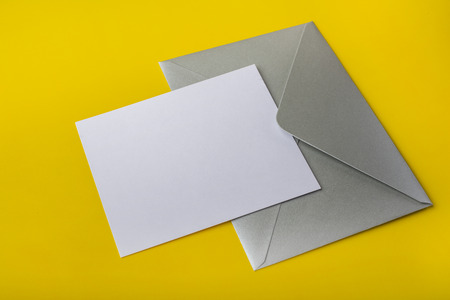 Mock-up letter or card with a silver envelope on a yellow background. Copy spaceの写真素材
