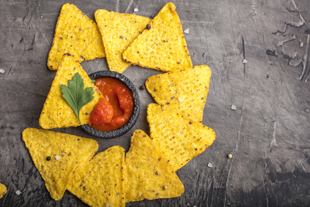 Tortilla Corn Chips or Nachos with sauce in a black bowl, on a dark background. View from above. Copy spaceの写真素材