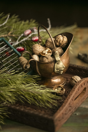 walnut kernel in a copper bowl on a wooden tray with branches of spruce. copy spaceの写真素材